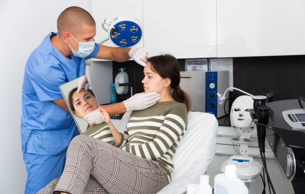 istock Cosmetologist examining female client face before procedure 1285221310