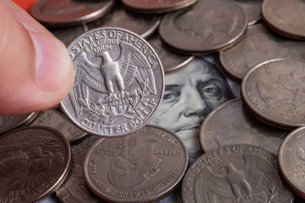 Several coins in denominations of 25 American cents from different years of issue lie on the bill in denominations of 100 dollars Several coins in denominations of 25 American cents from different years of issue lie on the bill in denominations of 100 dollars, leaving only the portrait of Benjamin Franklin visible dollar bill eagle stock pictures, royalty-free photos & images