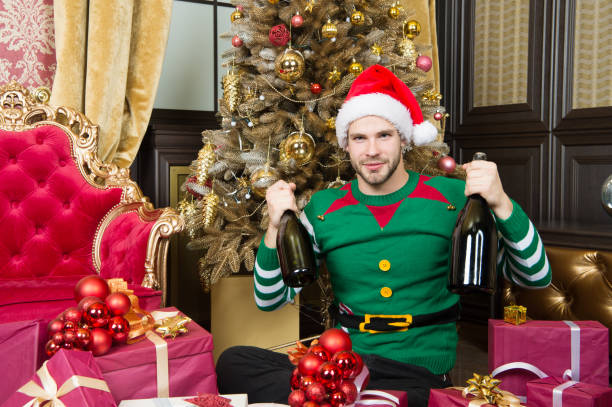 Man celebrate new year or christmas holiday. Santa claus and christmas gifts concept. Man wear santa hat elf clothes celebrate christmas interior decorated fir tree and gifts. Christmas magical time Man celebrate new year or christmas holiday. Santa claus and christmas gifts concept. Man wear santa hat elf clothes celebrate christmas interior decorated fir tree and gifts. Christmas magical time. elf photos stock pictures, royalty-free photos & images