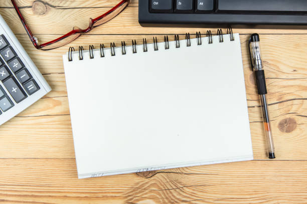 istock Open notebook, keyboard, glasses and a calculator on wooden background. 1285227814