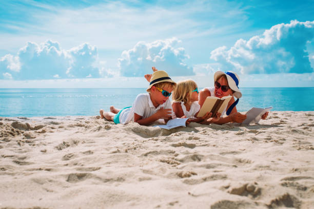 istock mother with son and daughter reading books at beach 1285229025