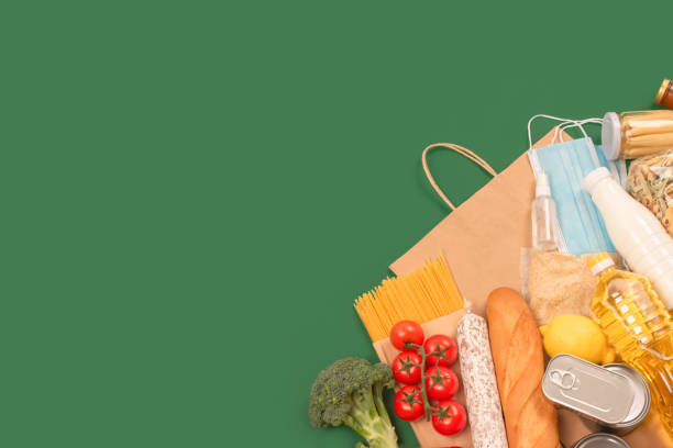 istock Flat lay composition with food and medicines donations on green background with copyspace - pasta, fresh vegatables, canned food, baguette, cooking oil. Food donations and food bank concept 1285231601