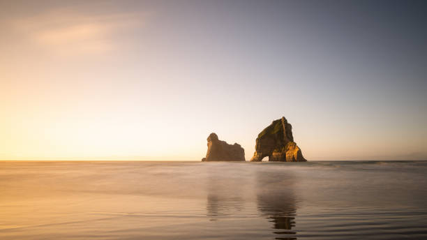 archway island sulla spiaggia di wharariki al tramonto, south island, nuova - golden bay foto e immagini stock