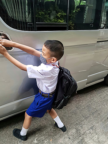 Boy, student, wearing mask Opening the door of the school bus to travel to school to study Prevention of Covit-19 Or the coronavirus
