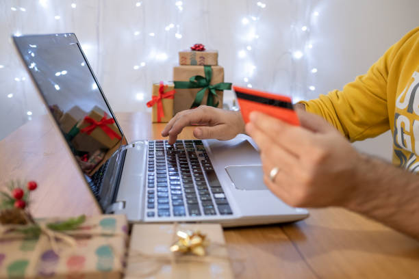 Hand of young man doing shopping online with credit card on leptop for christmas. stock photo