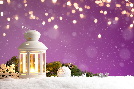 Christmas lantern with decorations on purple background with golden lights, copy space