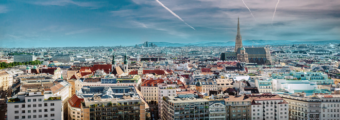 Picturesque view panorama of Vienna city, jet trail in the blue cloudy bright sky, sunny warm day during summertime. European townscape, Austria