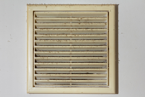 A layer of dust on the plastic ventilation grill in the kitchen wall. Clean ventilation at home