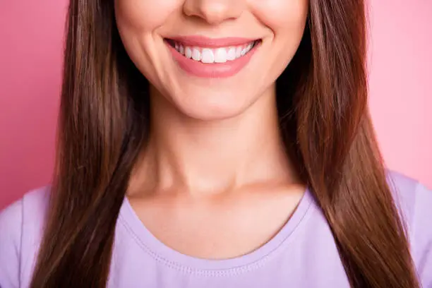 Closeup cropped photo of beautiful woman with brunette hair smiling with white teeth isolated on pastel pink color background.