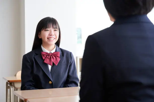 A Japanese junior high school girl meets with her teacher in the classroom