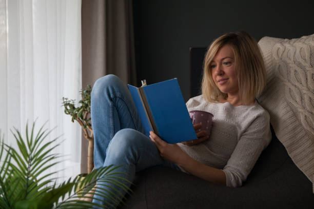 istock Relaxing woman reading a book and drinking tea at home 1285243503