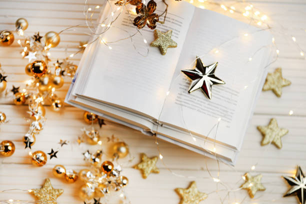Winter books.Winter cozy reading. A pile of white books, shining stars and garlands on a white wooden table.Cozy mood.books close up. Book pages macro and shining garland. Winter Season.Christmas book libros de invierno. lectura acogedora de invierno. un montón de libros blancos, estrellas brillantes y guirnaldas sobre una mesa de madera blanca. acogedor mood.books de cerca. páginas de libro macro y guirnalda brillante. winter season.libro de navidad
