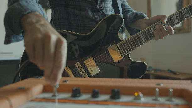 rockgitarrist spielt gitarre zu hause, einstecken - verstärker stock-fotos und bilder