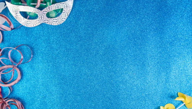 Brazilian carnival masks and props arranged on a shiny blue surface, top view.