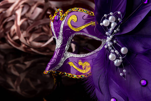 istock Carnival mask, lilas venetian mask on black surface with streamers, selective focus. 1285249310