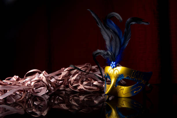 istock Carnival mask, golden and blue Venetian mask on black surface with streamers, selective focus. 1285249402