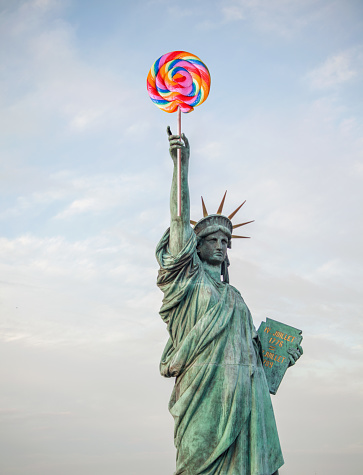 Digital montage photography of the statue of liberty holding a lollipop in her hands. Perfectly usable for all fun equality and liberation projects.