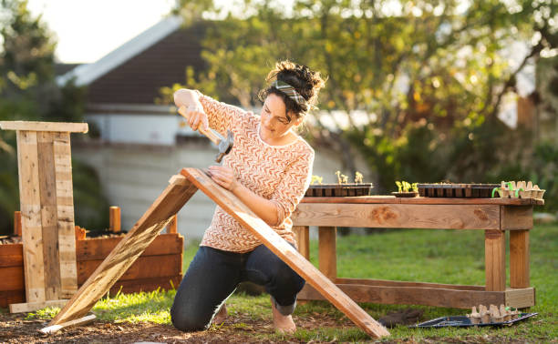 Young woman making a planting box outside in her yard