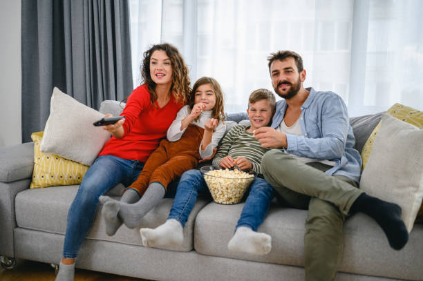 istock Family eating popcorn while watching tv at home 1285252359