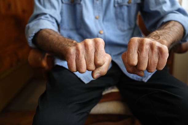 Very old, aged male hand as fist on blue background .Concept: \