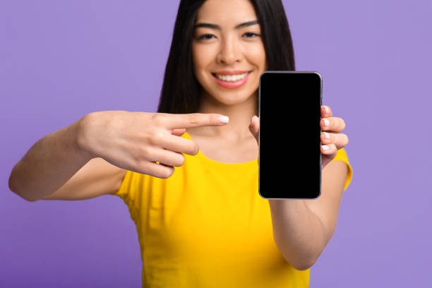 istock Positive Asian Lady Pointing On Blank Black Smartphone Screen, Mockup Image 1285255202