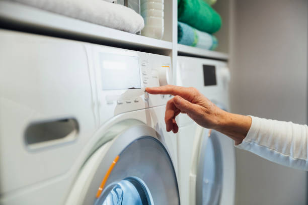 Which Wash To Choose A close-up of a female's hand choosing the best washing cycle for the clothes she is washing making sure to choose the most efficient one for energy consumption. water conservation photos stock pictures, royalty-free photos & images