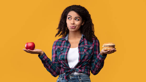 istock Hungry Black Lady Holding Burger And Apple Fruit 1285255278