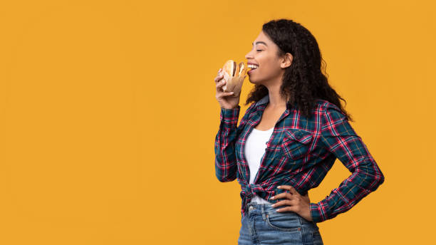 istock Funny African American Lady Eating Burger At Orange Studio 1285256206