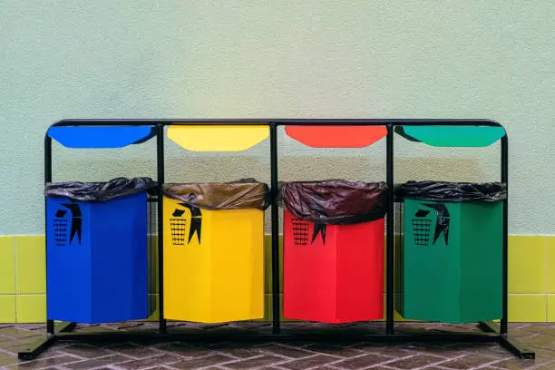 Photo of Separate collection of glass, metal, paper and plastic. Colored bins for separate garbage.