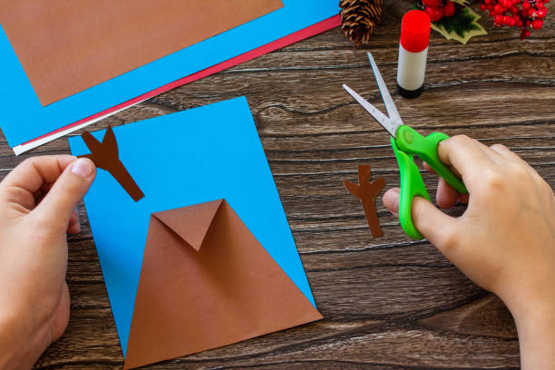 istock Instruction step 4. Merry greeting card with a Christmas deer on a wooden table. Handmade. Children's creativity project, crafts, crafts for kids. 1285258253