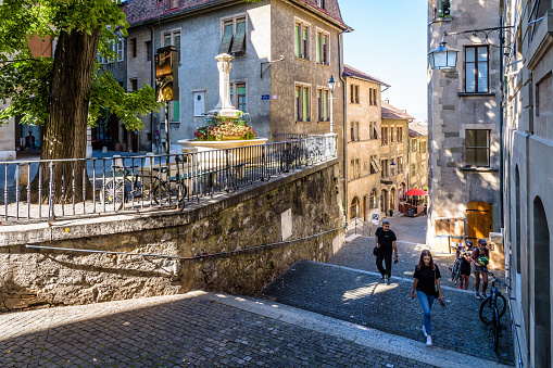 Geneva, Switzerland - September 4, 2020: People are going up the rue du Perron, a narrow steep street that leads to the upper part of the old town, situated on a hill.
