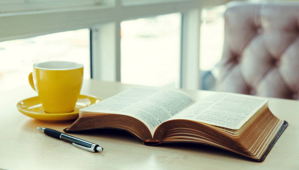 istock Open old book with yellow cup of coffee on the desk 1285260541