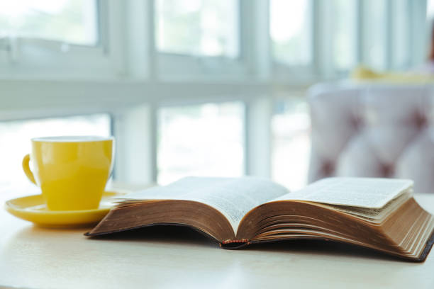 istock Open old book with yellow cup of coffee on the desk 1285260573