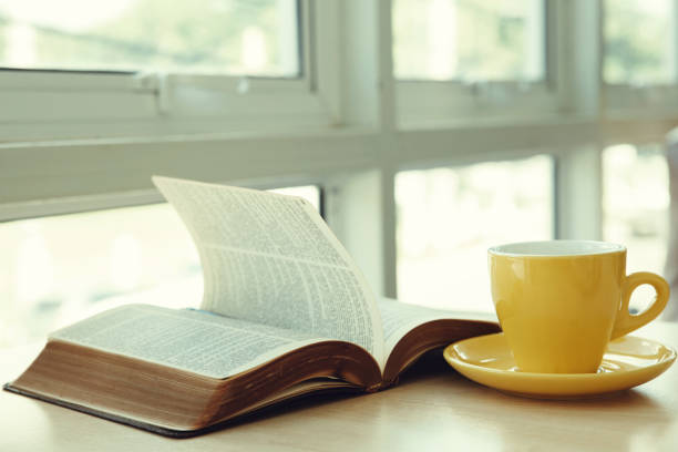 istock Open old book with yellow cup of coffee on the desk 1285260656