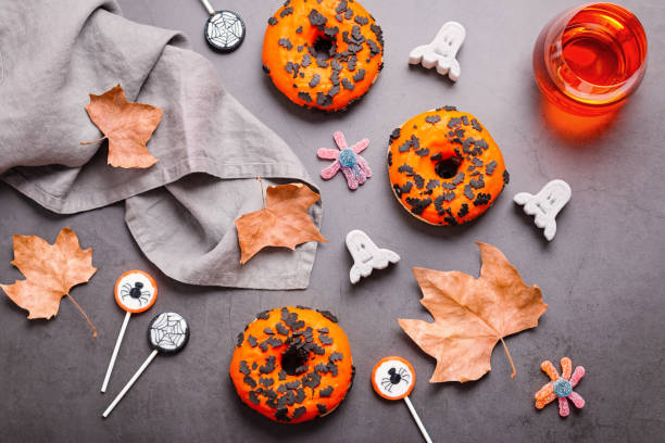 istock Pumpkin and chocolate donuts, spider lollipops, gummy candy and marshmallows on grey stone - Halloween candy flat lay on gray stone table, top view, kids party concept 1285261957