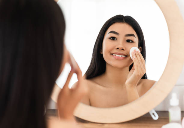 istock Smiling asian woman cleaning her face, using cotton pads 1285263399
