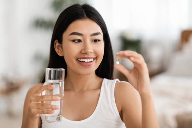 istock Happy Asian Woman Taking Pill In Morning 1285263555