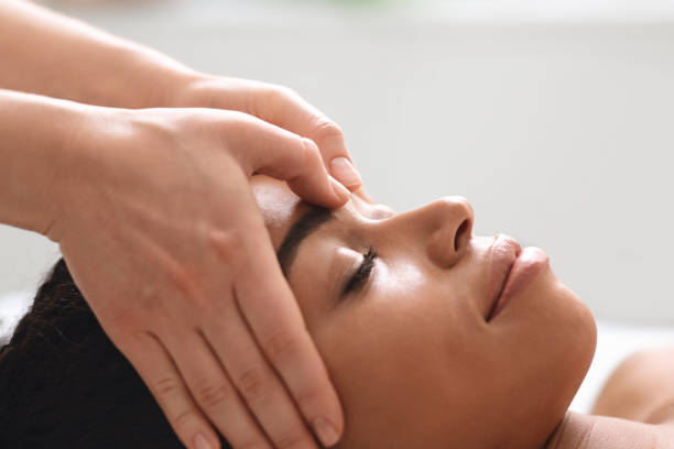 istock Massage therapist rubbing african american lady forehead 1285263663