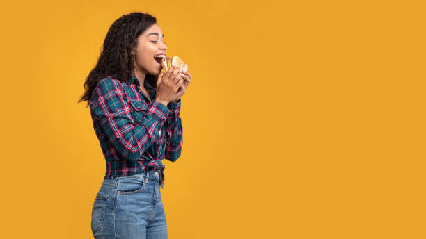 istock Hungry African American Lady Eating Burger At Studio 1285263667