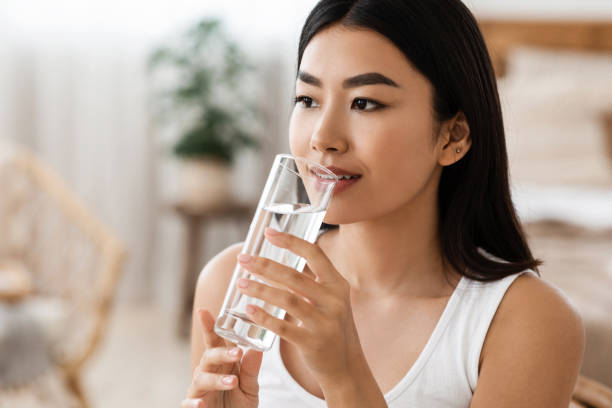 istock Young attractive asian woman drinking water, copy psace 1285263678
