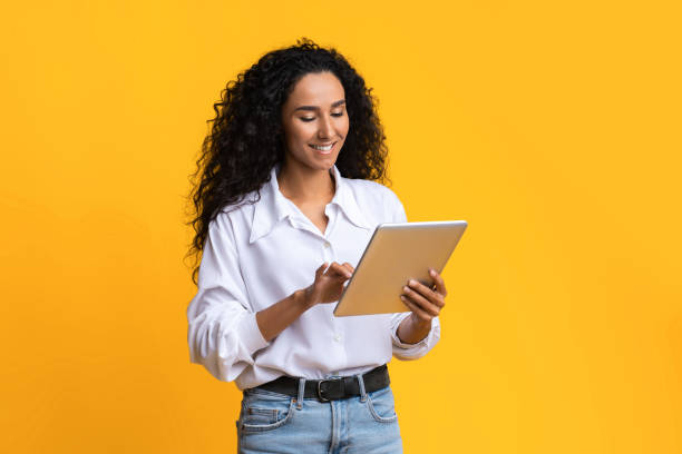 istock Young Woman Using Digital Tablet, Browsing Social Networks Over Yellow Studio Background 1285265480