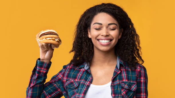 istock Smiling African American Lady Showing Burger At Studio 1285265829