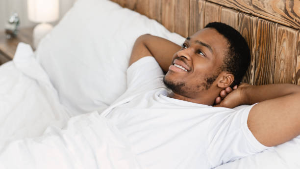 istock Happy African Guy Lying Awake In Bed In The Morning 1285265942