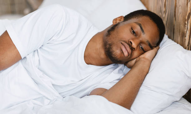 istock Depressed African American Guy Lying Awake In Bed At Home 1285266769
