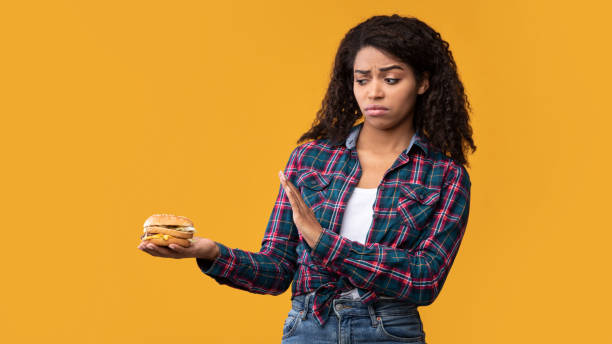 istock Black Lady Holding Burger And Showing Stop Gesture 1285266879