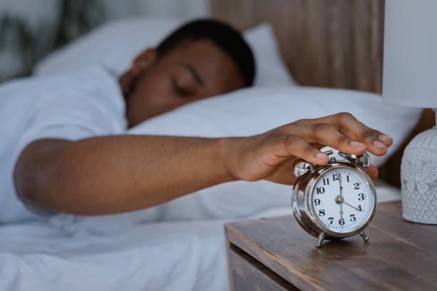 istock African Man Awakening Turning Off Alarm Clock Lying In Bed 1285267046