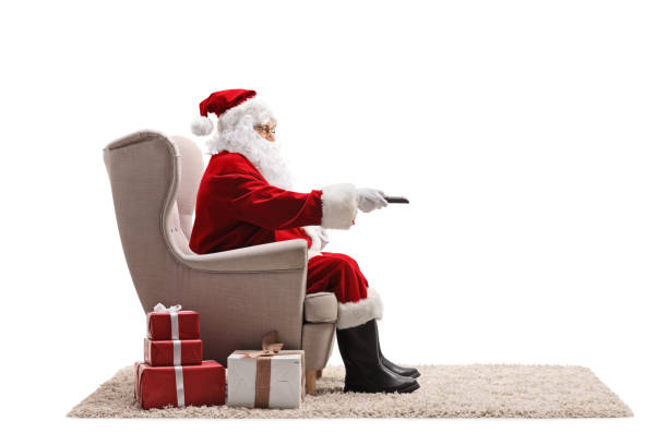 santa claus sitting in an armchair and holding a remote control - remote television movie box imagens e fotografias de stock