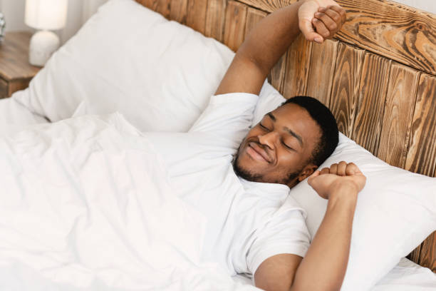 istock Rested Black Man Waking Up Lying In Bed At Home 1285267127