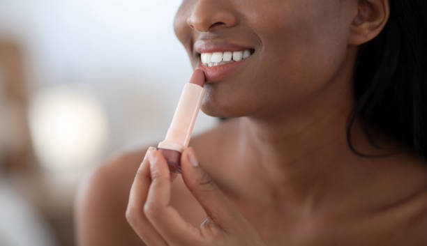 sorrindo jovem linda senhora afro-americana aplicando batom de cor nua nos lábios se preparem pela manhã - mirror women kissing human face - fotografias e filmes do acervo