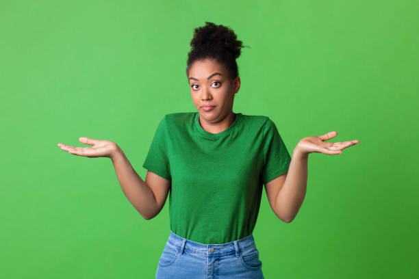 confused puzzled black young lady shrugging at studio - thinking green imagens e fotografias de stock
